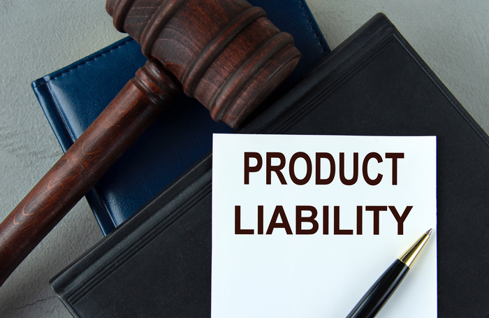 PRODUCT LIABILITY - words on a white sheet with leather notebooks, a judge's hammer and a pen.
